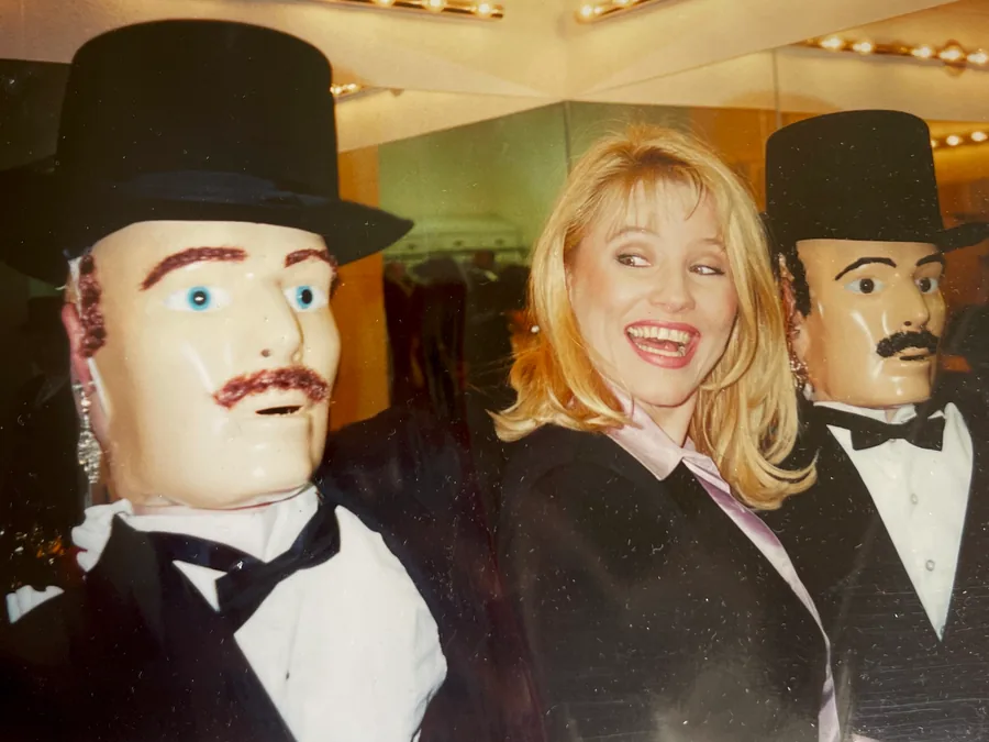 Raynor van der Merwe laughing between two top-hatted mannequin figures under marquee lights