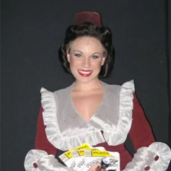 Kelly Moran in costume for The Producers holding a prop tray