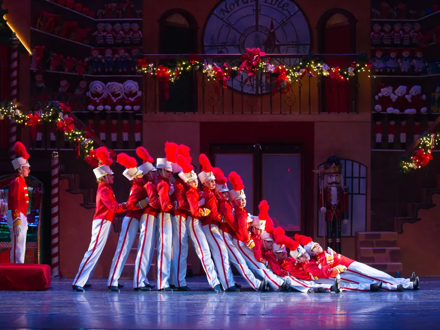 A line of ETAP toy soldiers in red and white falling backward like dominoes in Santa's workshop.