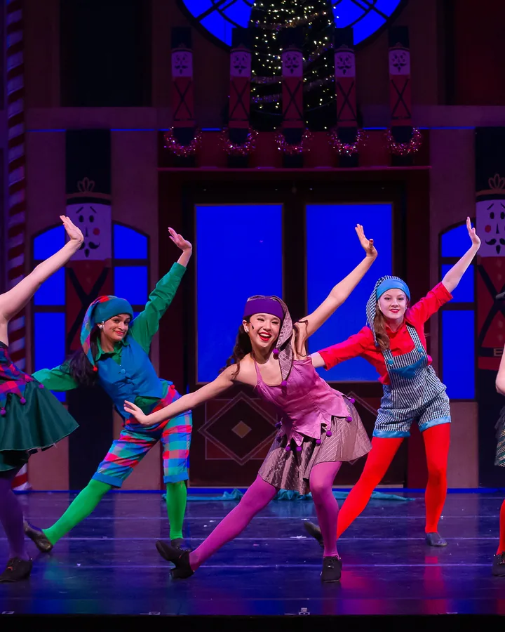 ETAP elves in bright holiday costumes posing mid-dance in Santa's workshop.